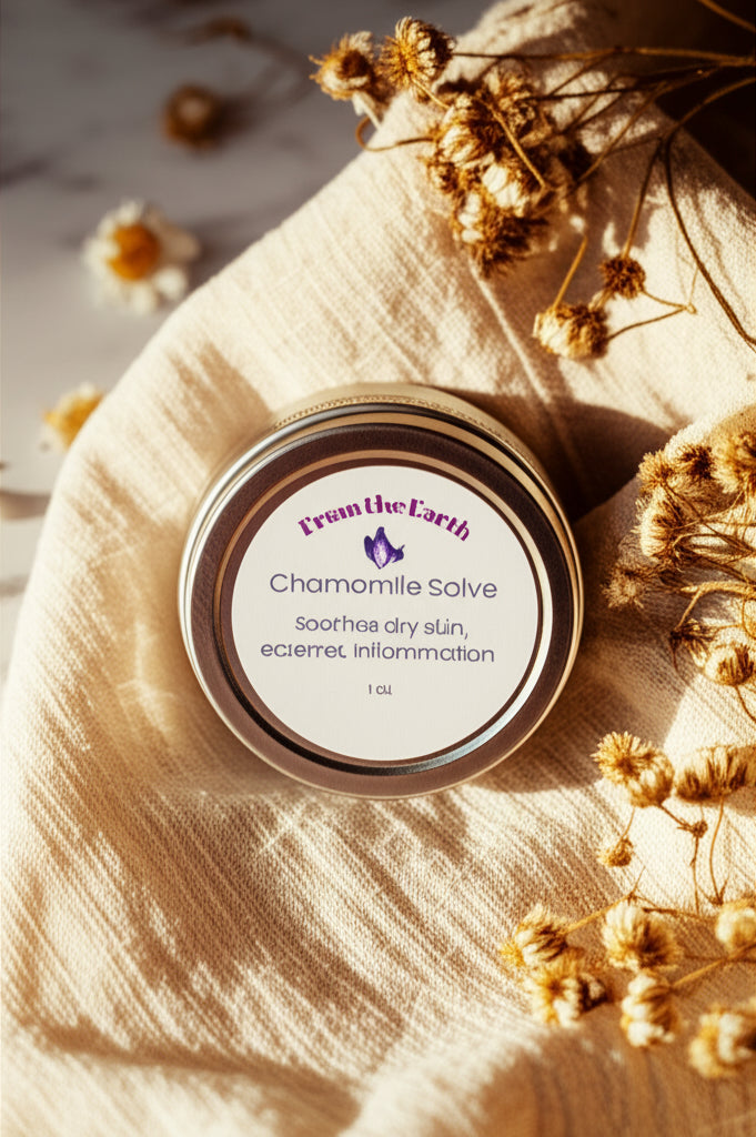 Jar of 'Chamomile Salve' from 'From the Earth' on a beige fabric with dried flowers.